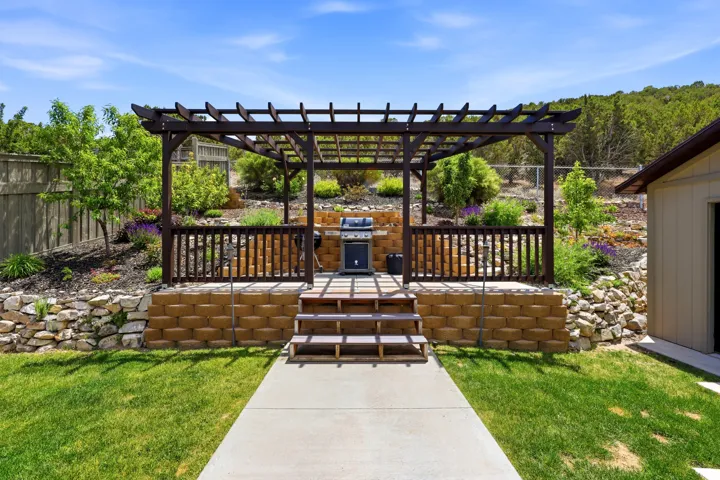 Outdoor pergola-covered patio featuring trex stairs.  Backyard mountains.