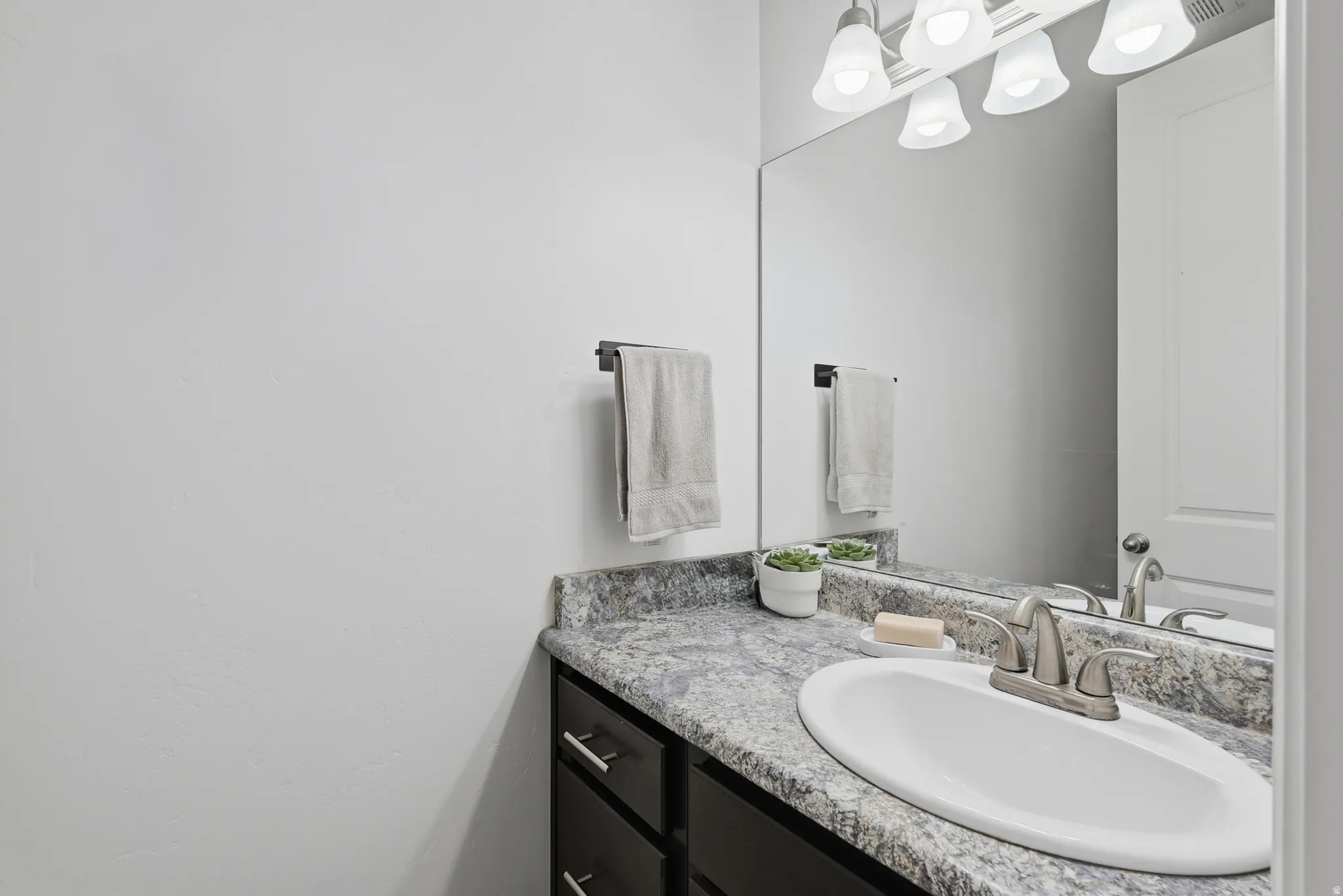 Bathroom vanity featuring a speckled countertop, integrated sink, and brushed nickel faucet