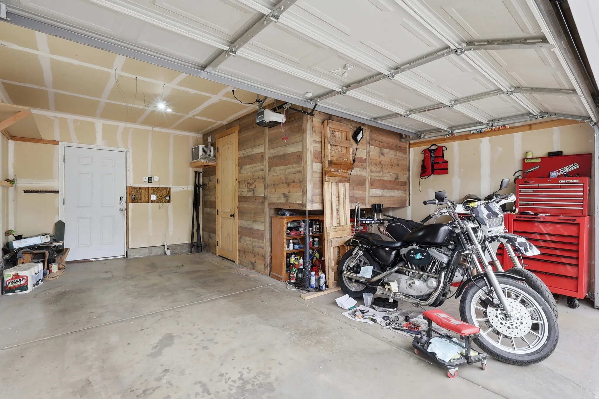 Spacious garage featuring a concrete floor, overhead lighting, and an automatic garage door opener