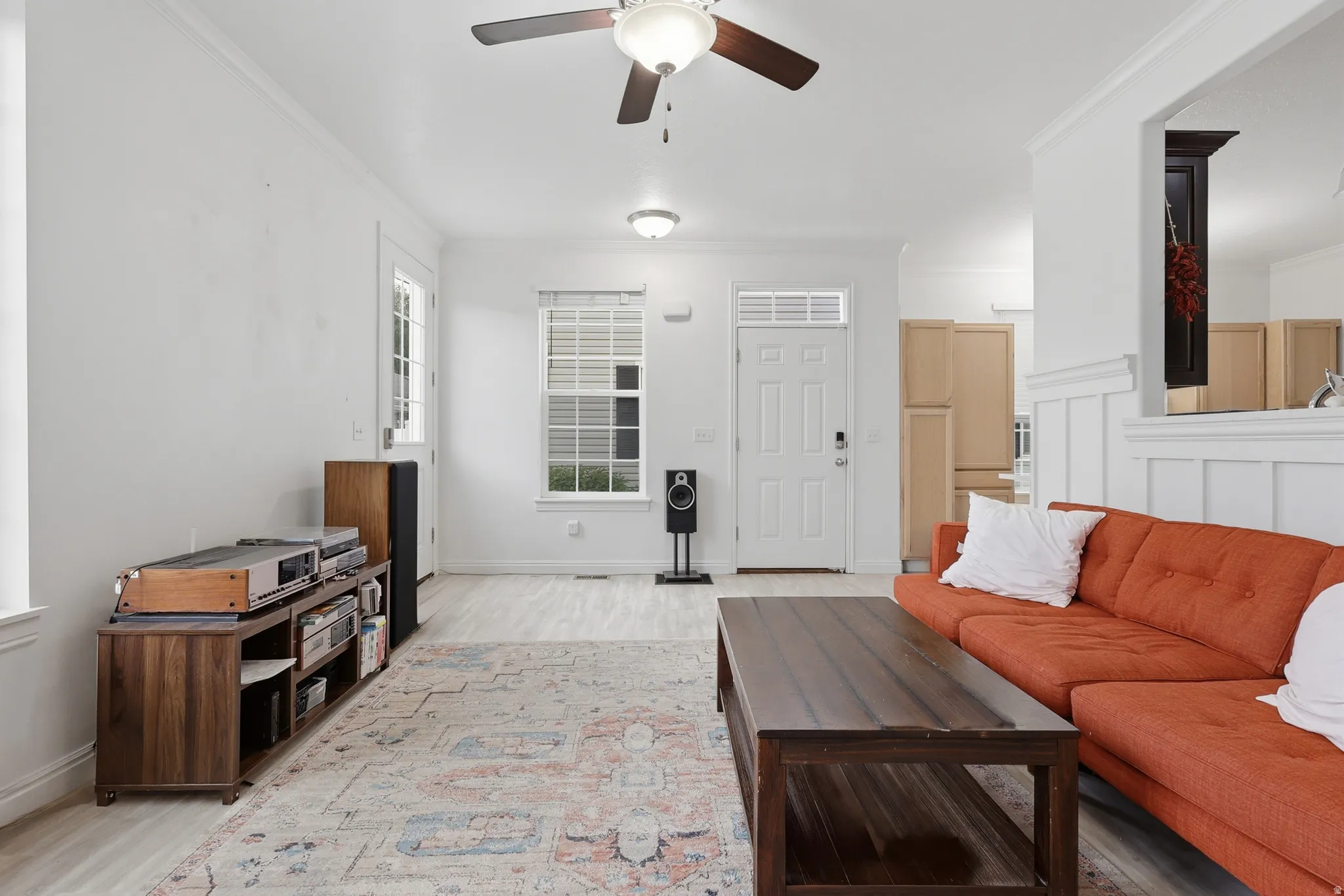 Open-concept living space featuring wood-finish flooring, white walls, and a ceiling fan with integrated lighting