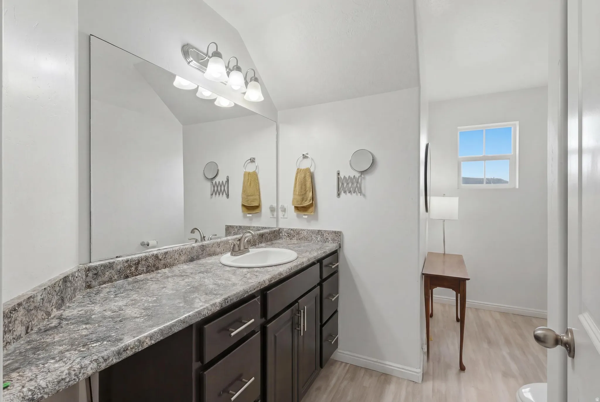 Bathroom vanity featuring a single basin sink, speckled countertop, and dark wood cabinetry