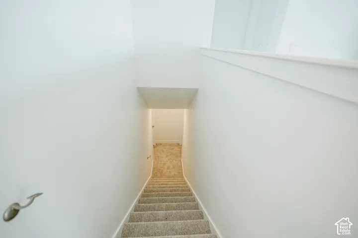 Carpeted staircase with light-toned walls and a modern brushed nickel handrail