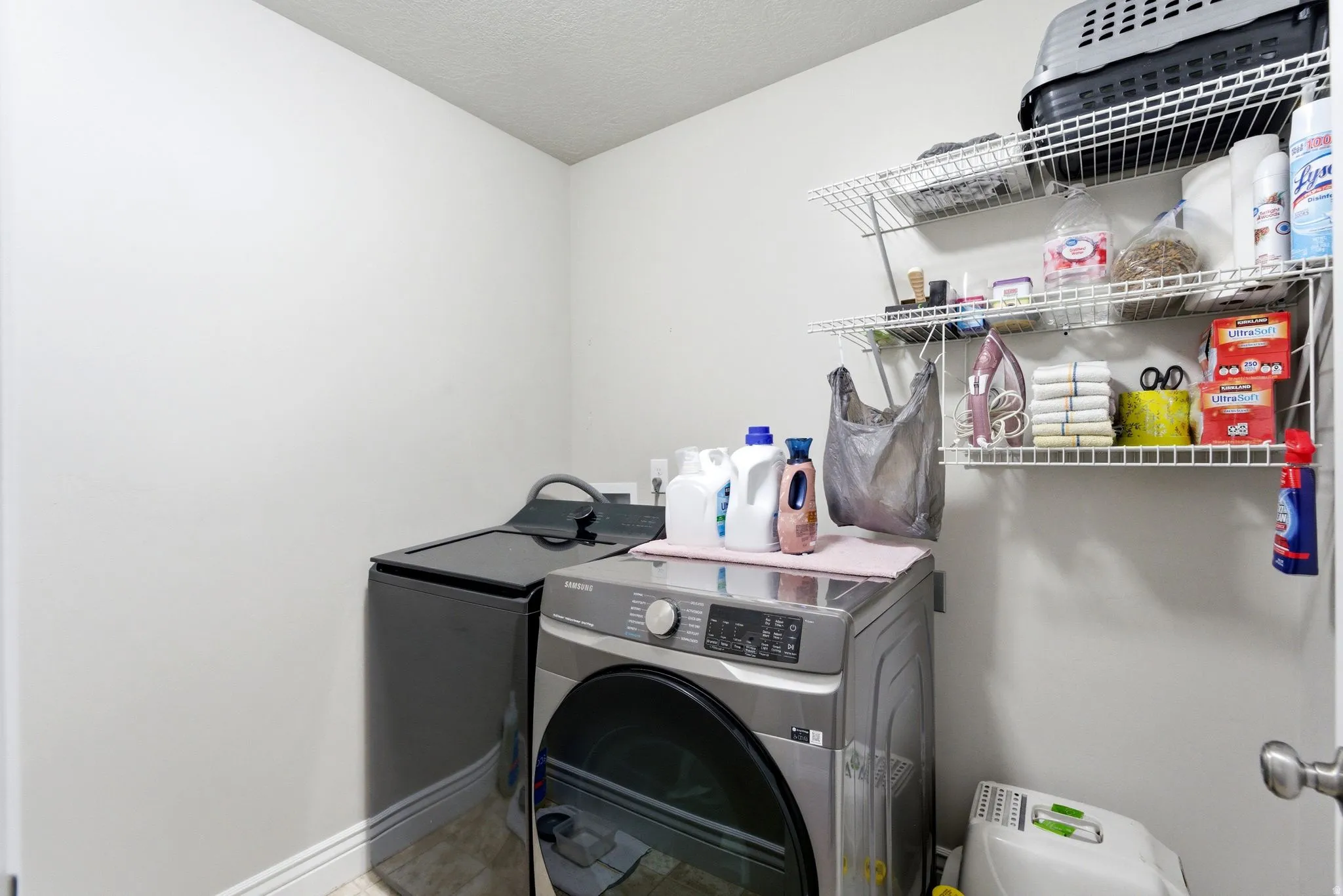 Dedicated laundry area featuring a front-load washing machine and a top-load washing machine