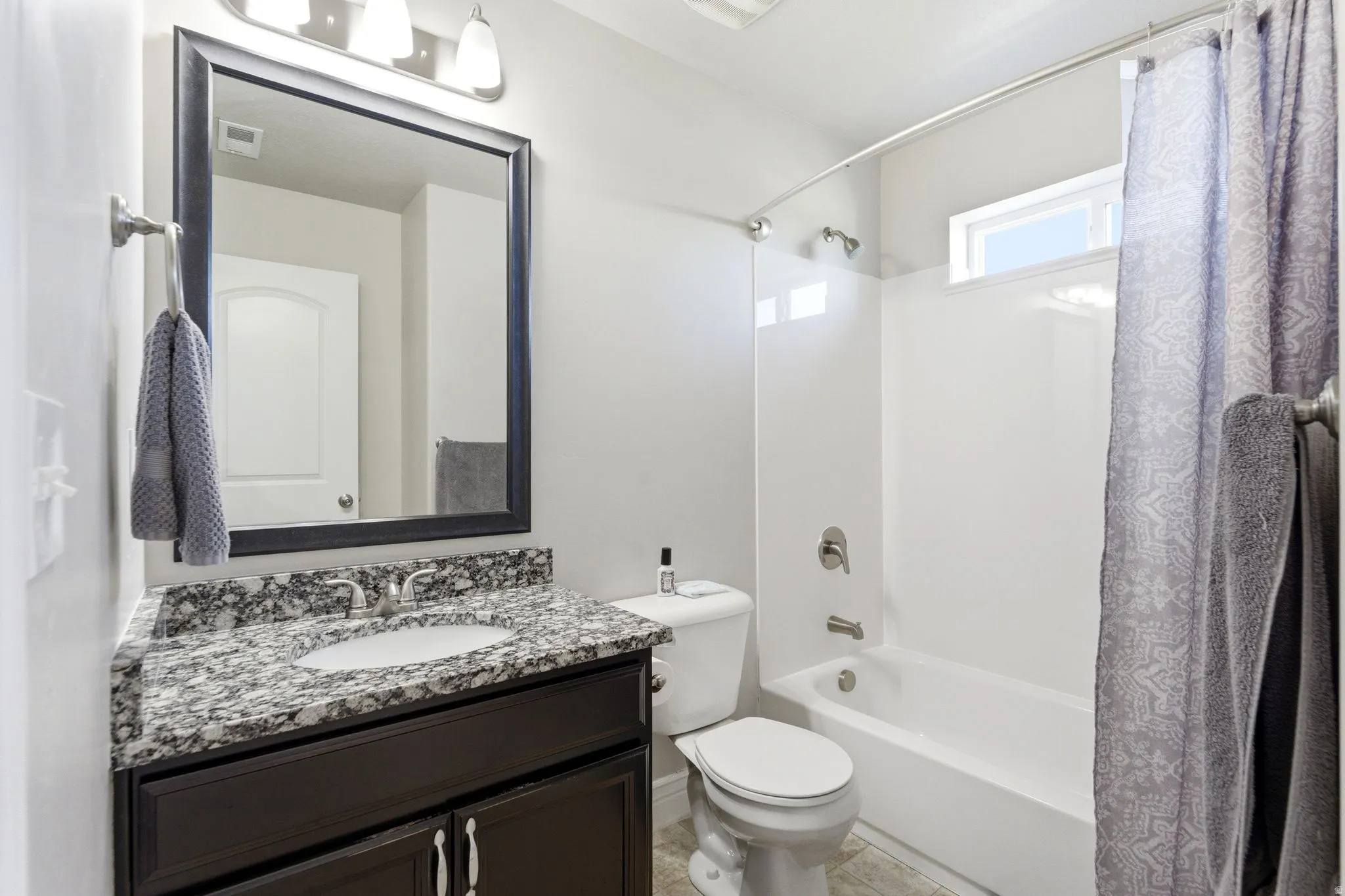 Bathroom vanity with granite-style countertop, undermount sink, and dark wood-finish cabinetry