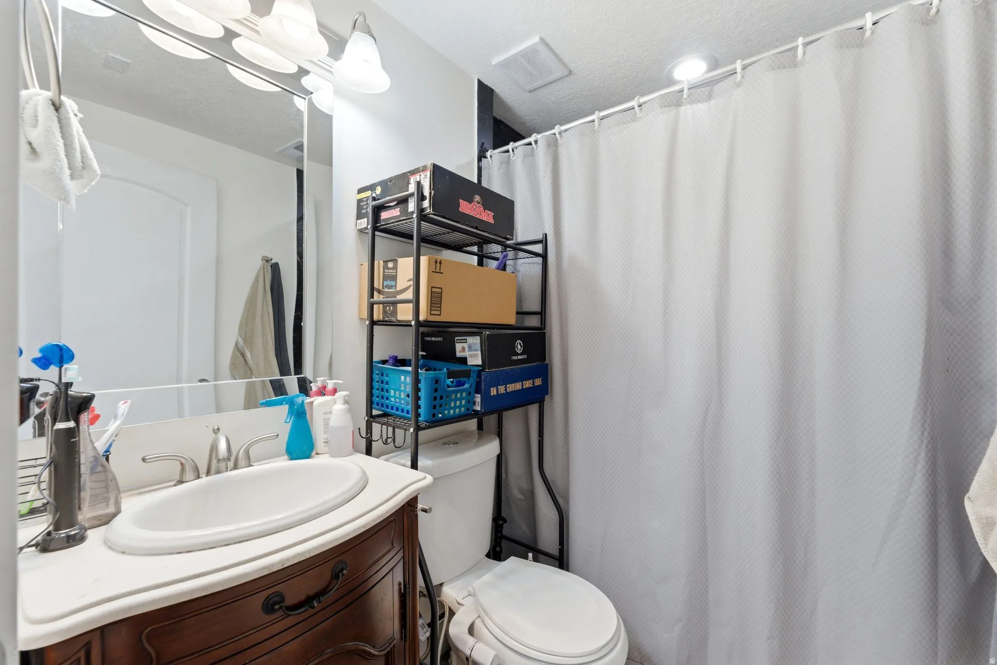 Bathroom featuring a vanity with an oval basin, a light-colored countertop, and a dark wood-finish base
