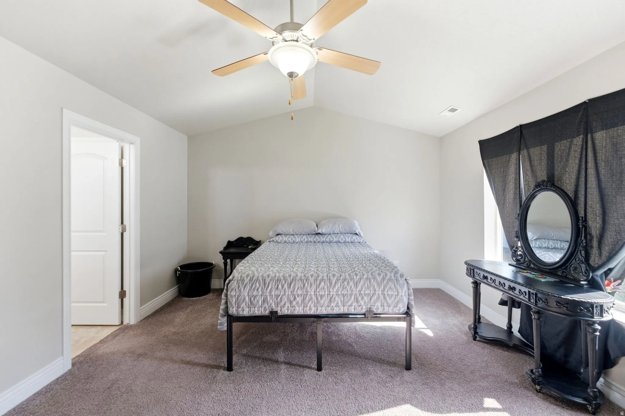 Carpeted room featuring a ceiling fan with light fixture, vaulted ceiling, and white trim