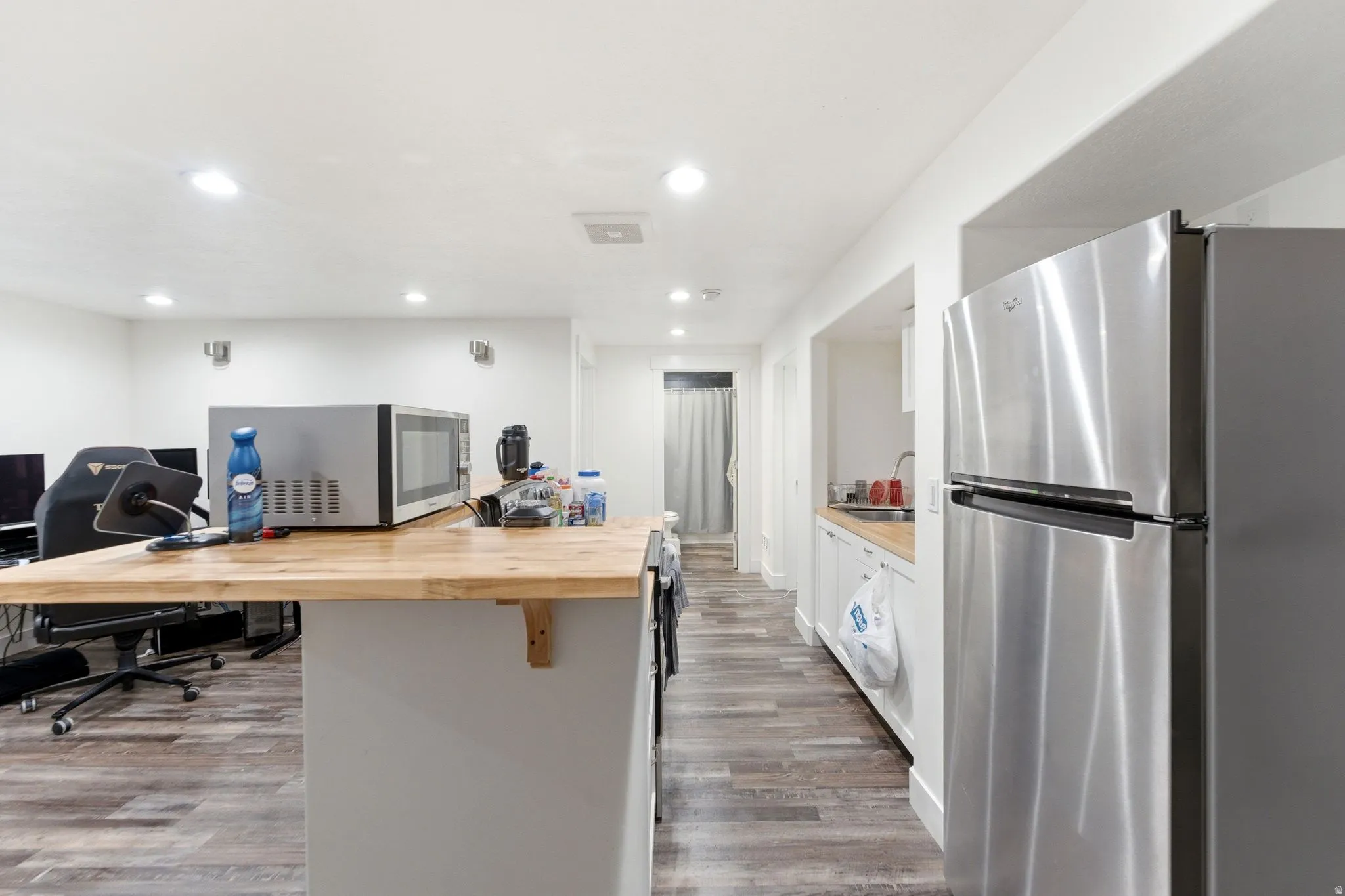 Kitchenette featuring stainless steel refrigerator, white cabinetry, and wood-finish countertop