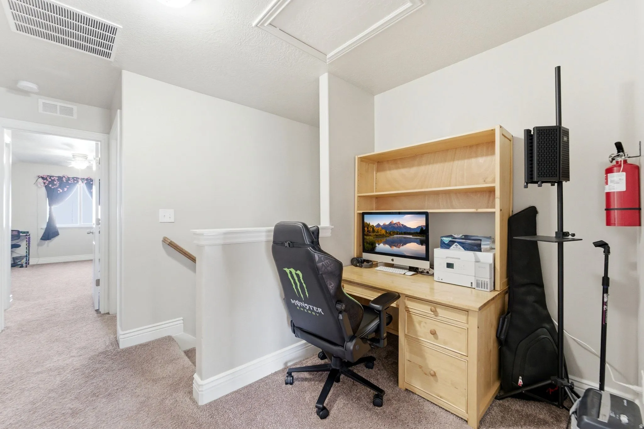 Loft area featuring a built-in wood-finish desk with hutch, neutral carpet flooring, and white painted walls