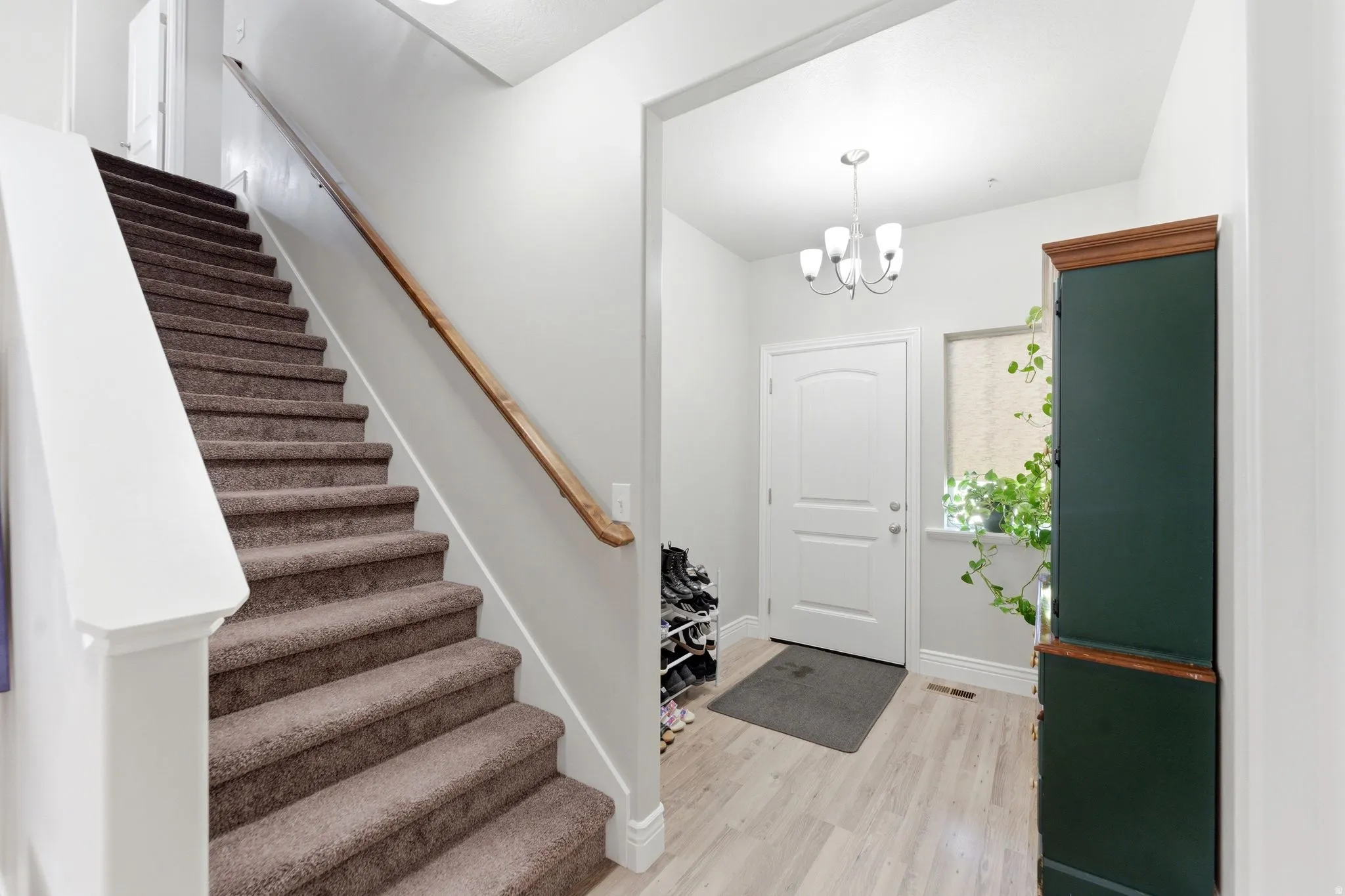 Carpeted staircase with white risers and a wood handrail