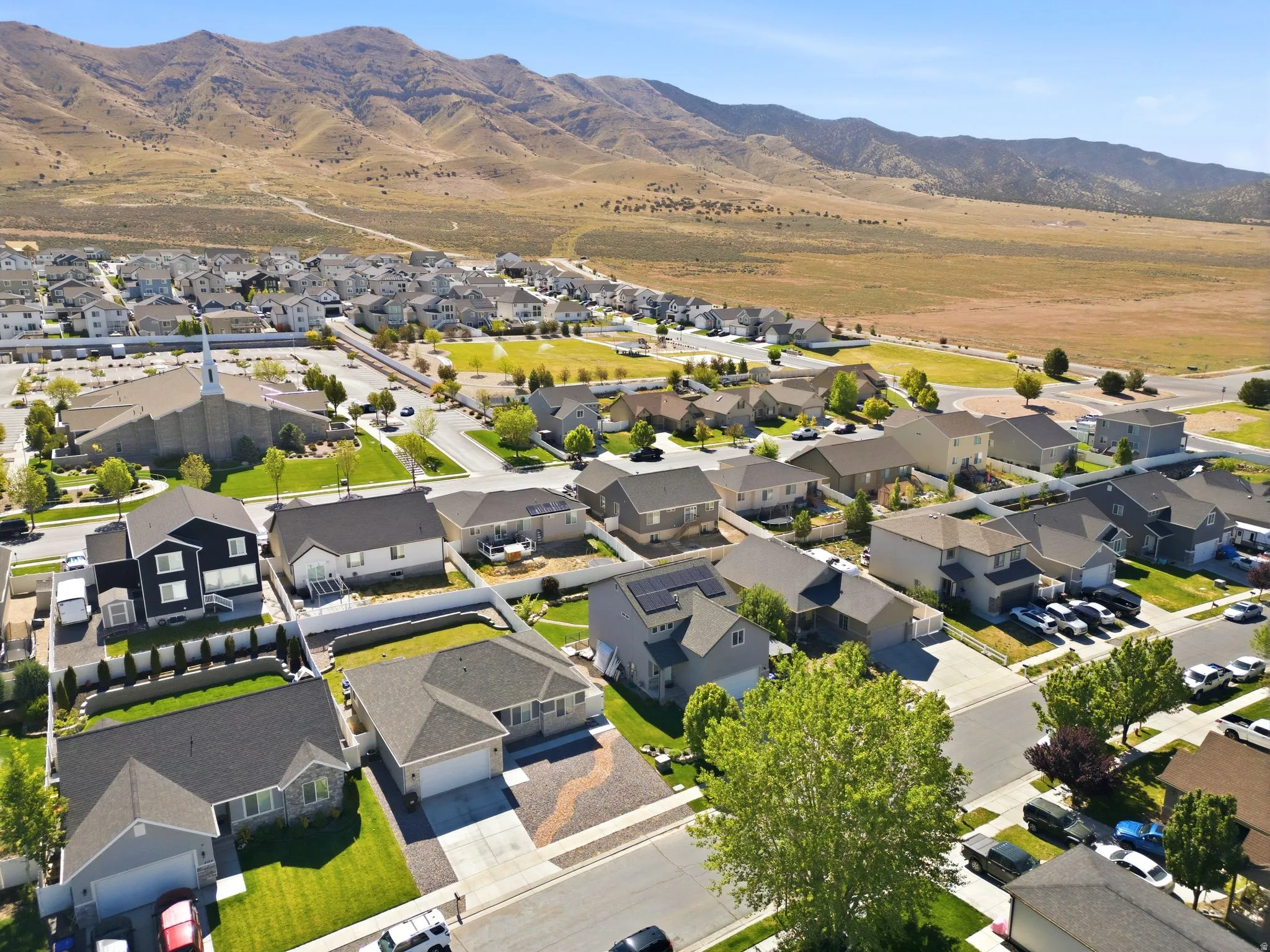 Expansive residential development featuring a variety of single-family homes with diverse architectural styles, paved roadways, and manicured green spaces