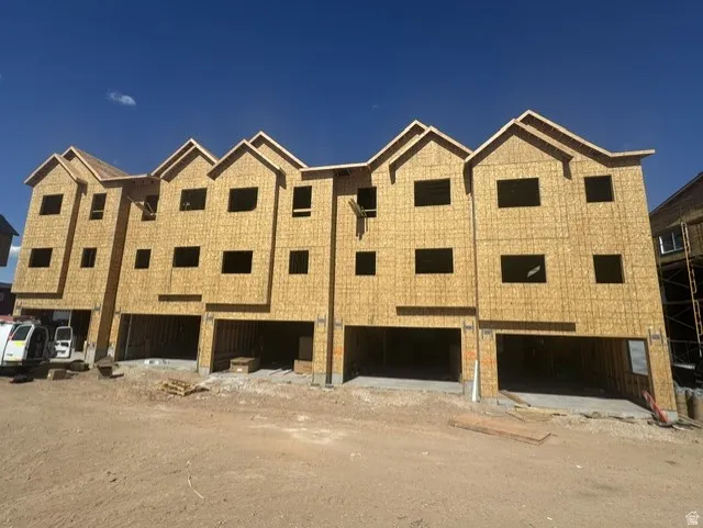 Multi-level residential structures featuring rough plywood sheathing, multiple window openings, and individual ground-level garage spaces