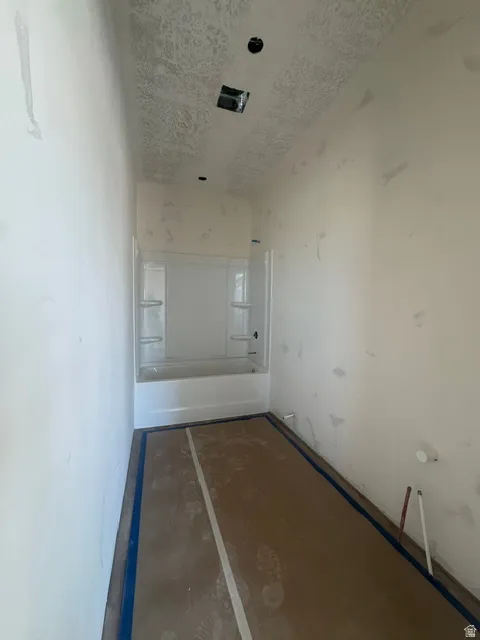 Bathroom space featuring a white bathtub and shower surround, textured ceiling