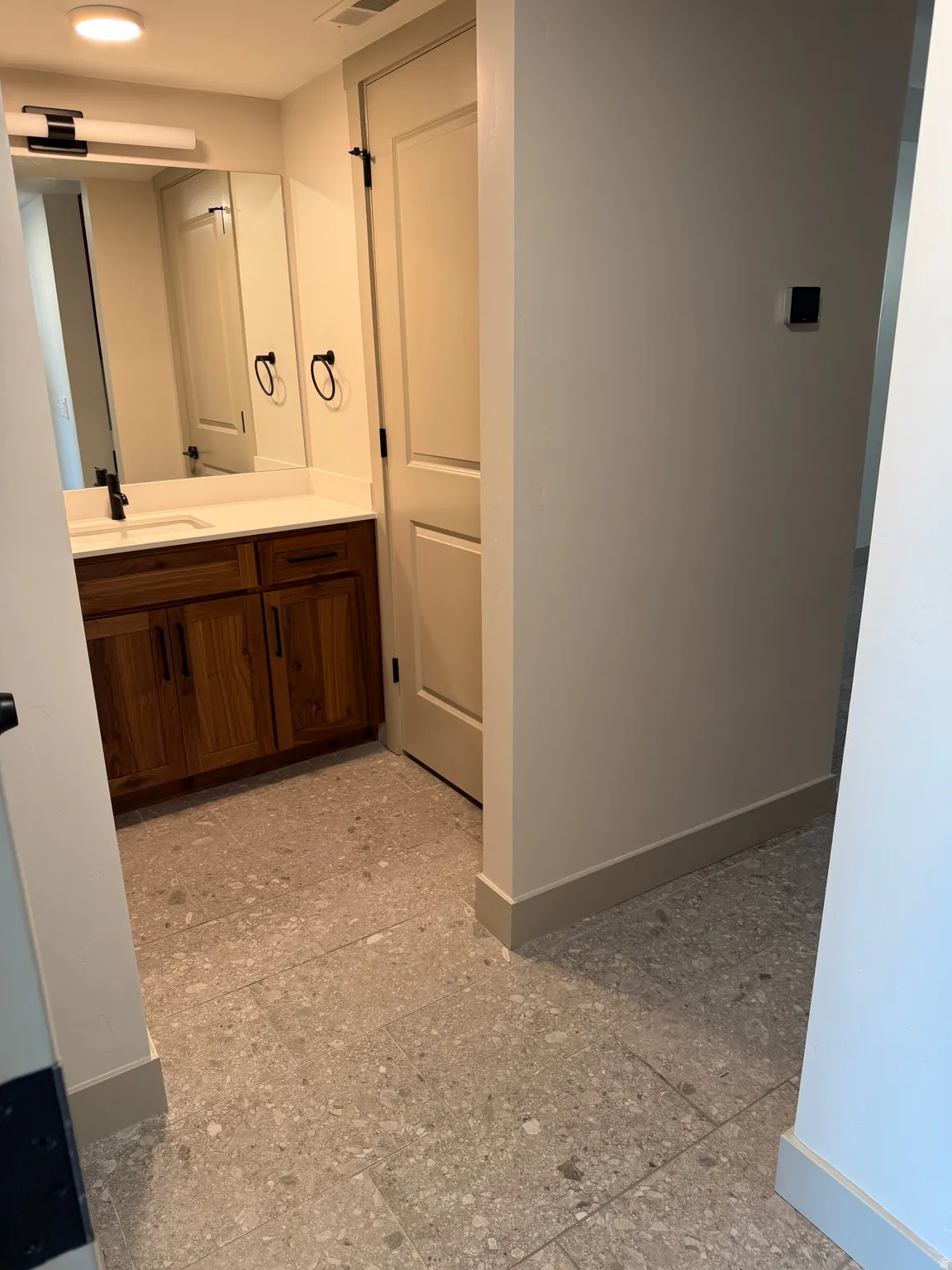 Bathroom vanity featuring a wood-finish cabinet, white countertop, and integrated sink