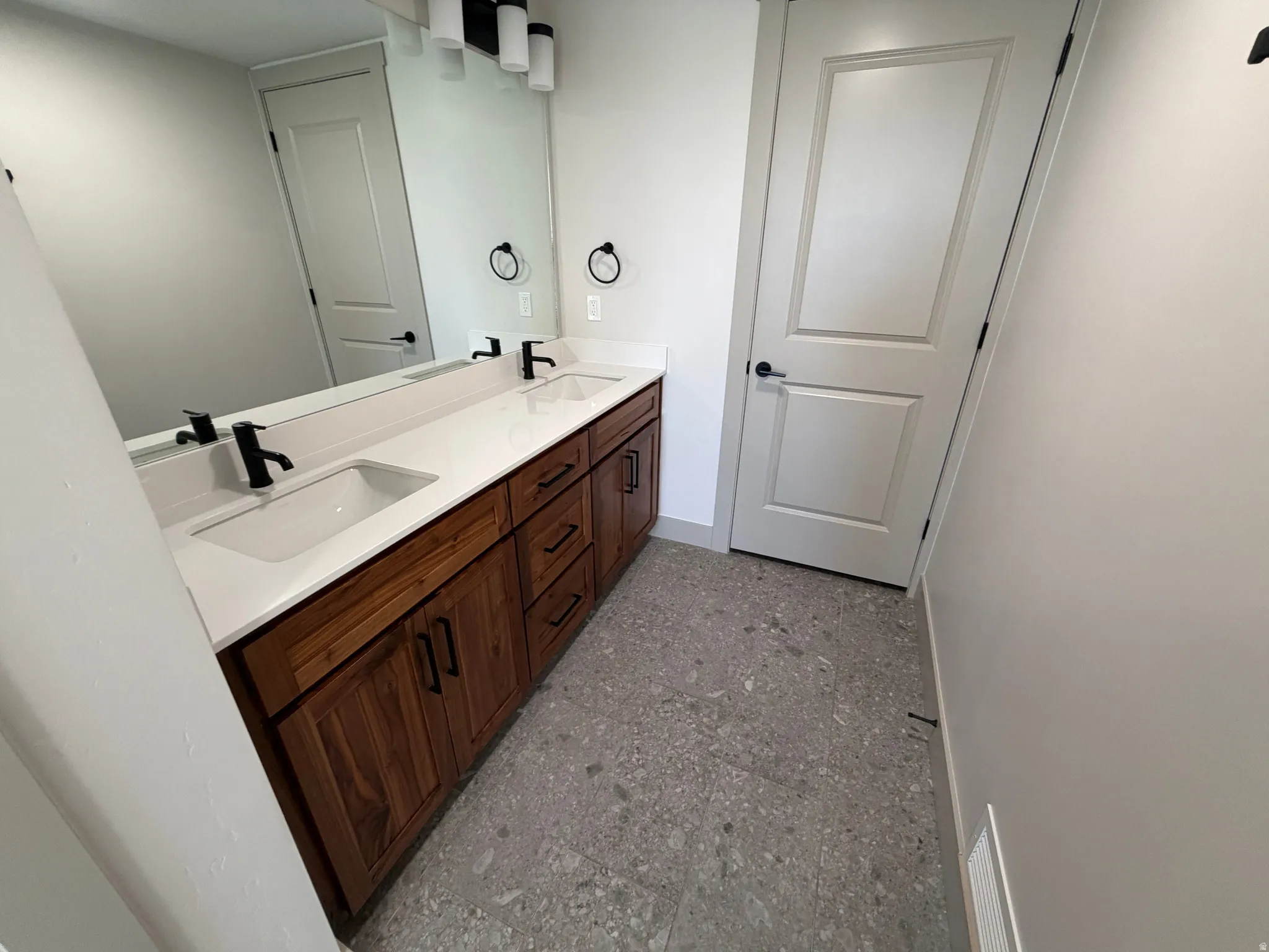 Double vanity featuring undermount sinks, white countertops, and dark wood-finish cabinetry with matte black hardware