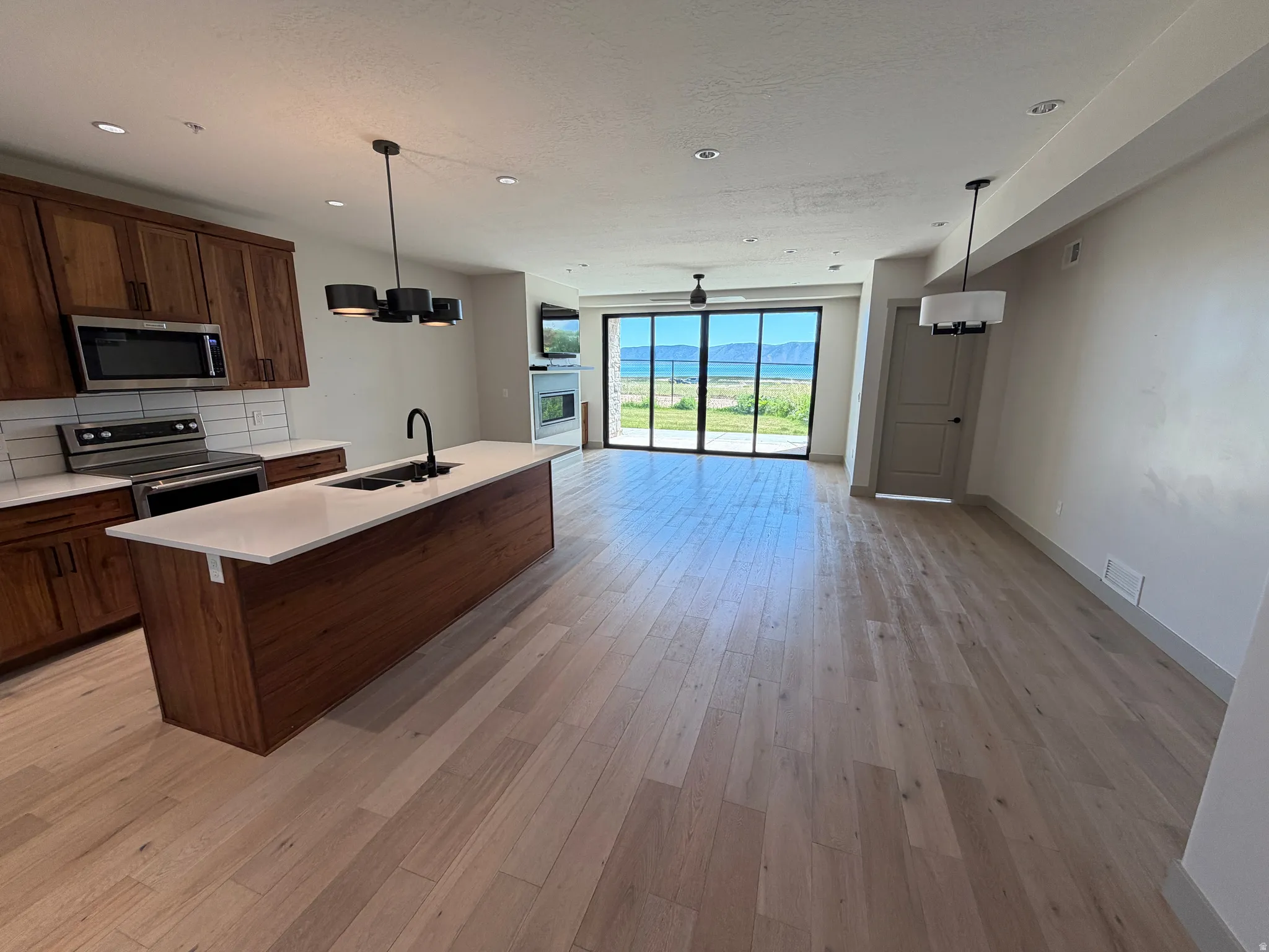 Spacious living area featuring light wood-finish flooring and a contemporary kitchen