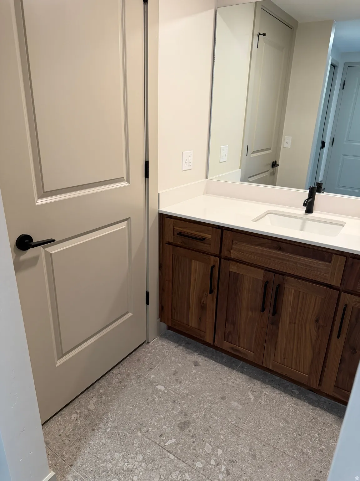 Bathroom vanity featuring a quartz countertop, integrated sink, and matte black faucet