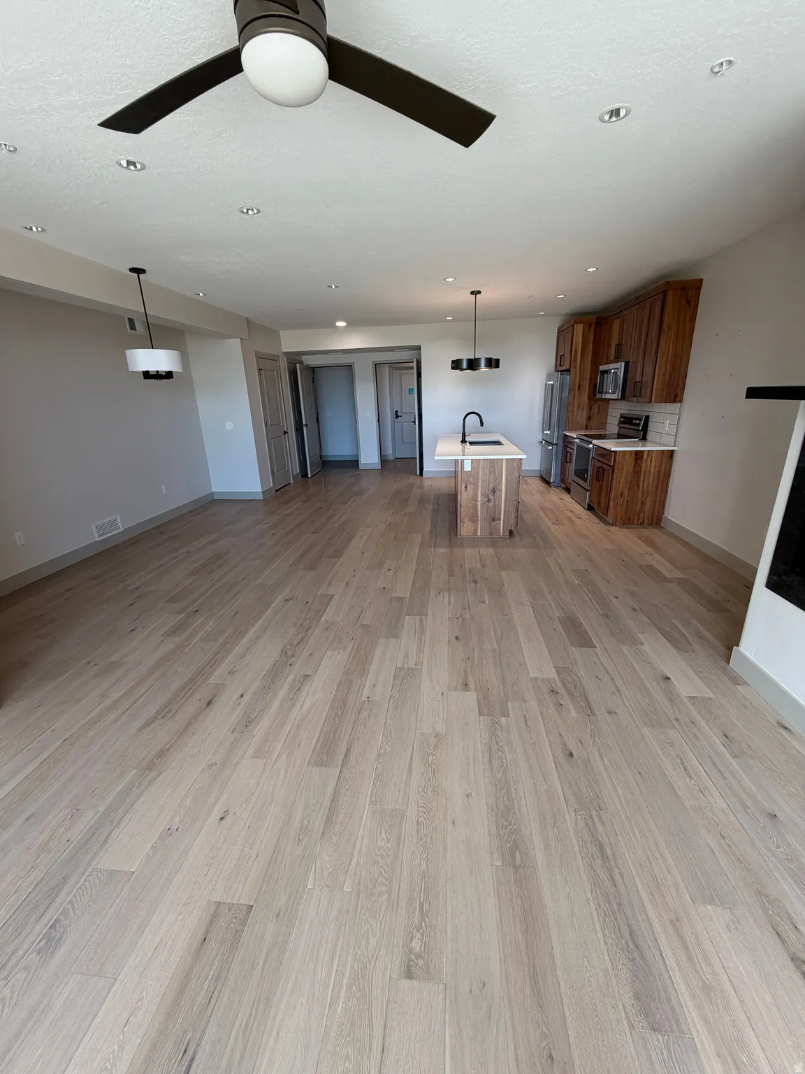 Open-concept living space featuring wide plank wood-finish flooring, recessed lighting, and a contemporary ceiling fan