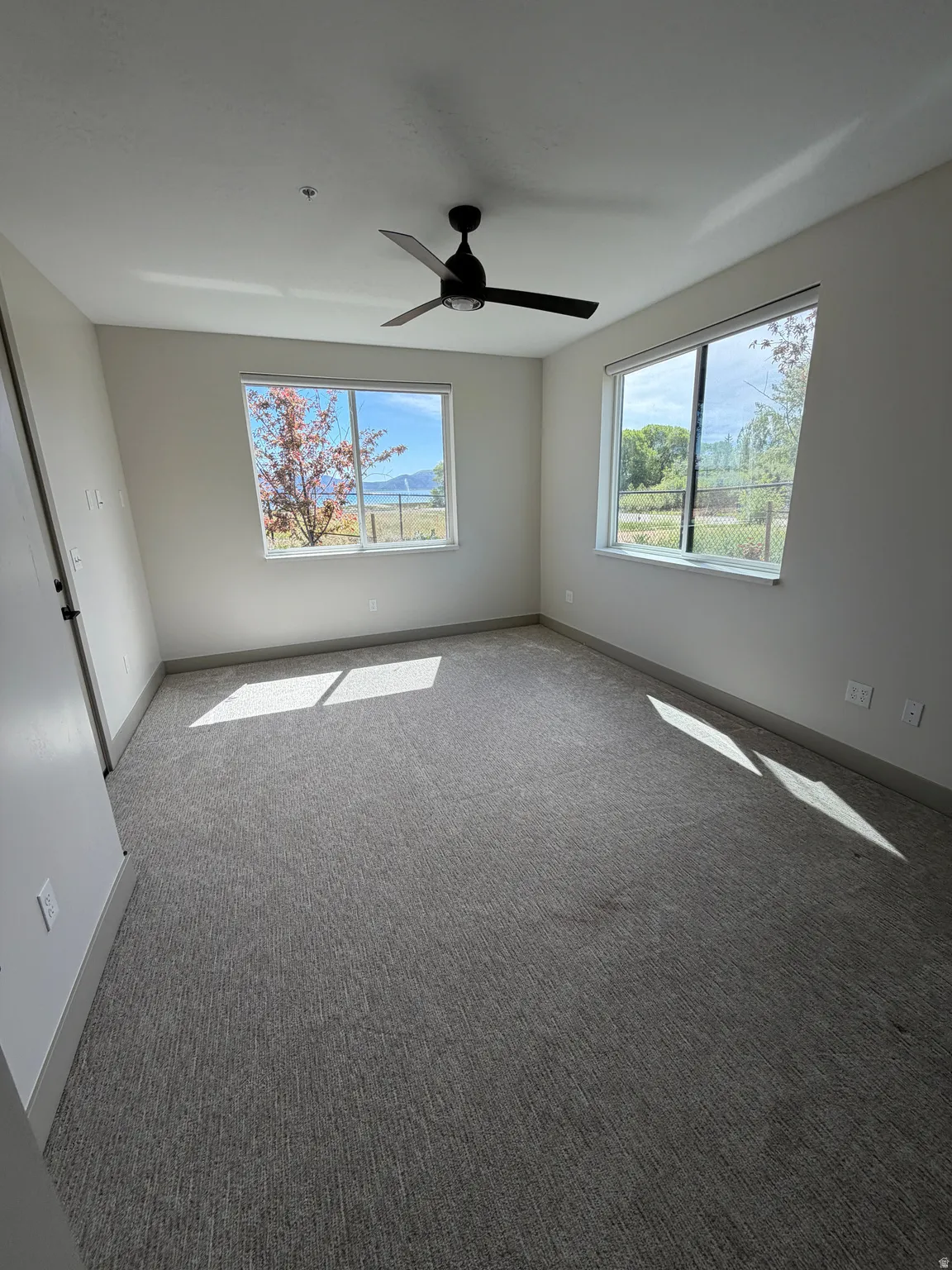 Spacious room with gray textured carpet and light neutral wall paint