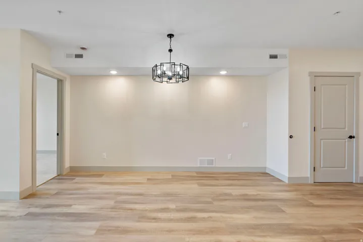 Spacious room featuring wood-finish flooring, recessed lighting, and a modern geometric chandelier