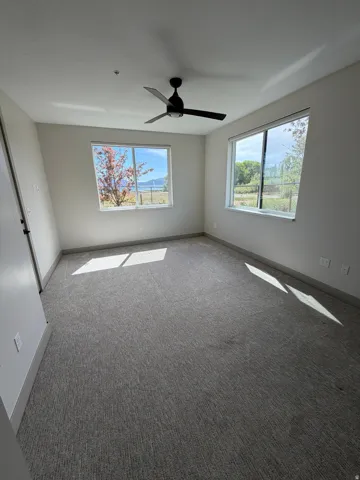 Spacious room with gray textured carpet and light neutral wall paint