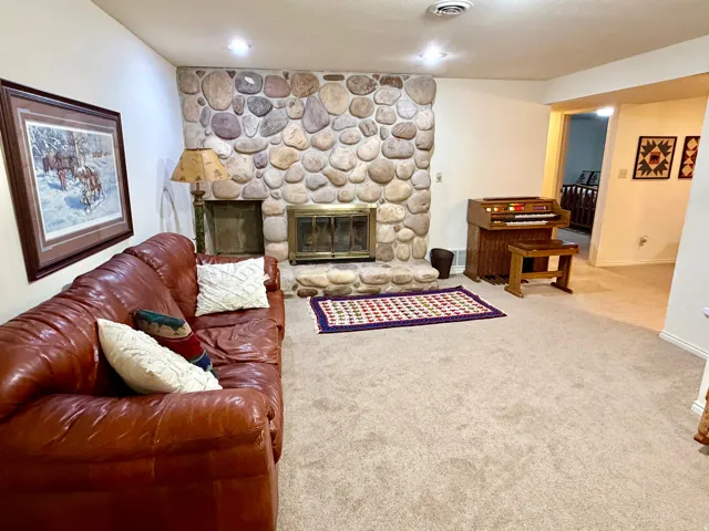 River rock fireplace with a brass firebox, hearth, and built-in wood storage
