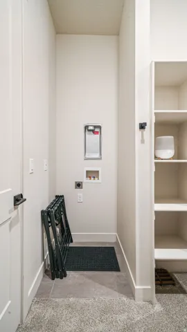 Dedicated laundry area featuring a tile floor, white walls, and built-in shelving