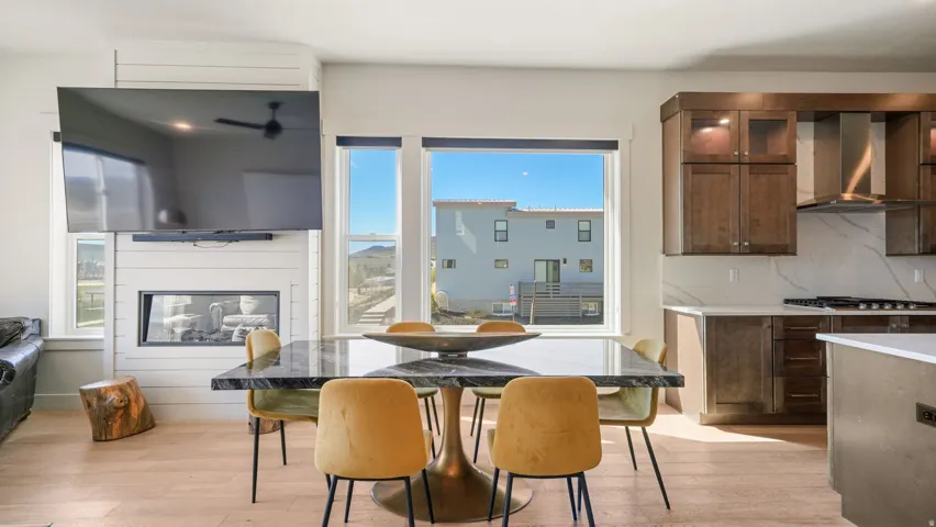 Open-concept living space featuring wood-finish flooring, a contemporary fireplace with shiplap surround, and large windows providing abundant natural light