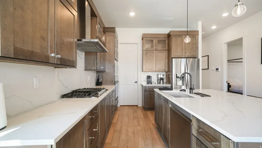 Contemporary kitchen featuring light wood-finish cabinetry, white veined countertops, and wood-finish flooring