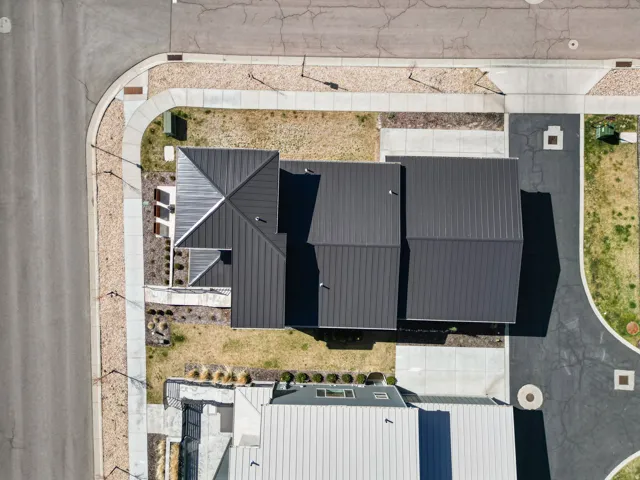 Contemporary property featuring a dark metal roof, clean lines, a corner lot position, and a paved driveway