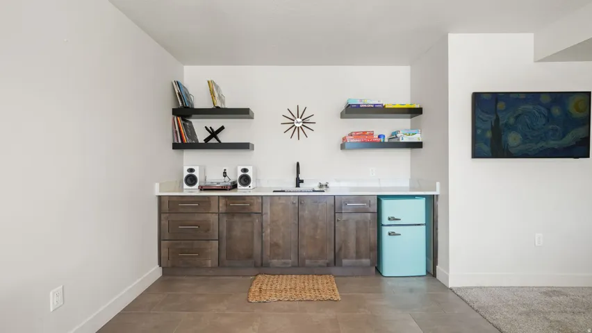 Wet bar featuring stained wood cabinetry, a white countertop, and a built-in sink with a matte black faucet