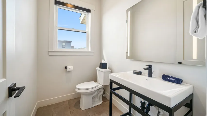 Contemporary bathroom featuring a floating vanity with a rectangular basin, matte black faucet, and an illuminated mirrored medicine cabinet