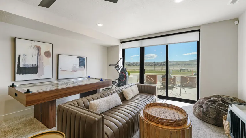 Spacious entertainment area with a shuffleboard table, large glass sliding doors, and a neutral color palette
