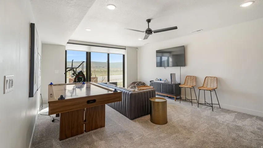 Spacious entertainment room featuring full-height windows, recessed lighting, and a ceiling fan