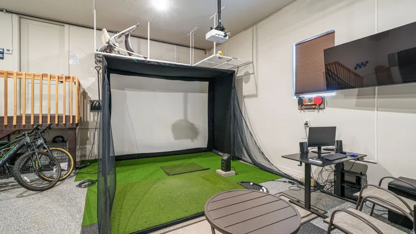 Dedicated indoor golf simulator with an artificial turf hitting area and projection screen