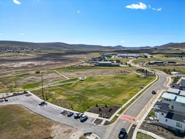 Community green space with a paved walking path, surrounded by developing residential structures and distant commercial buildings
