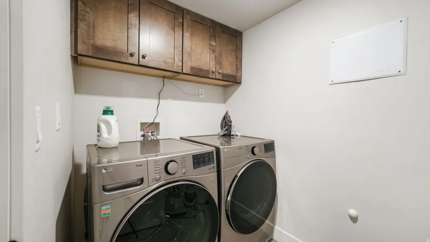 Dedicated laundry space featuring overhead wood-finish cabinetry