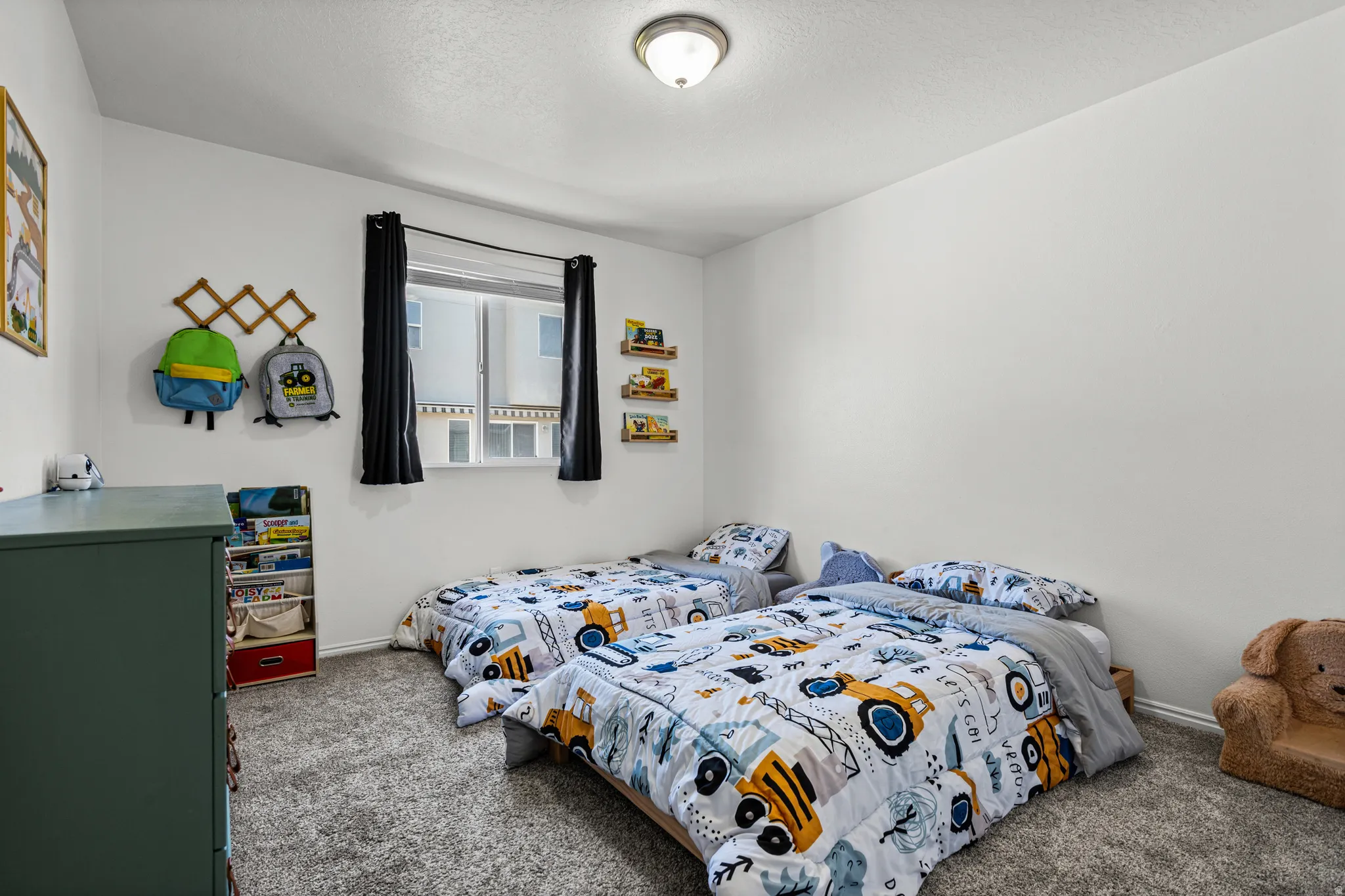Interior room featuring light gray carpet, white walls, a single window with dark drapery, and a ceiling-mounted light fixture