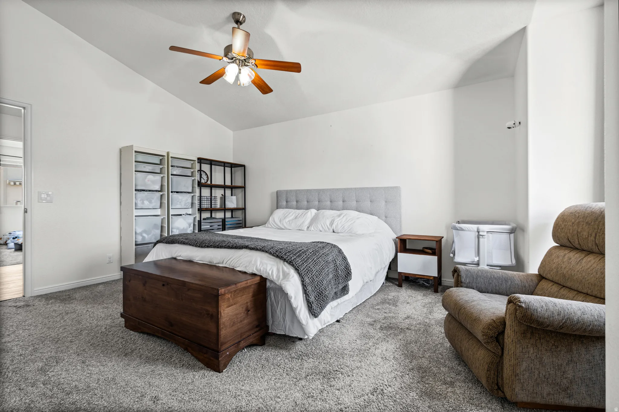 Vaulted ceiling bedroom featuring light gray carpet flooring and a ceiling fan with integrated lighting