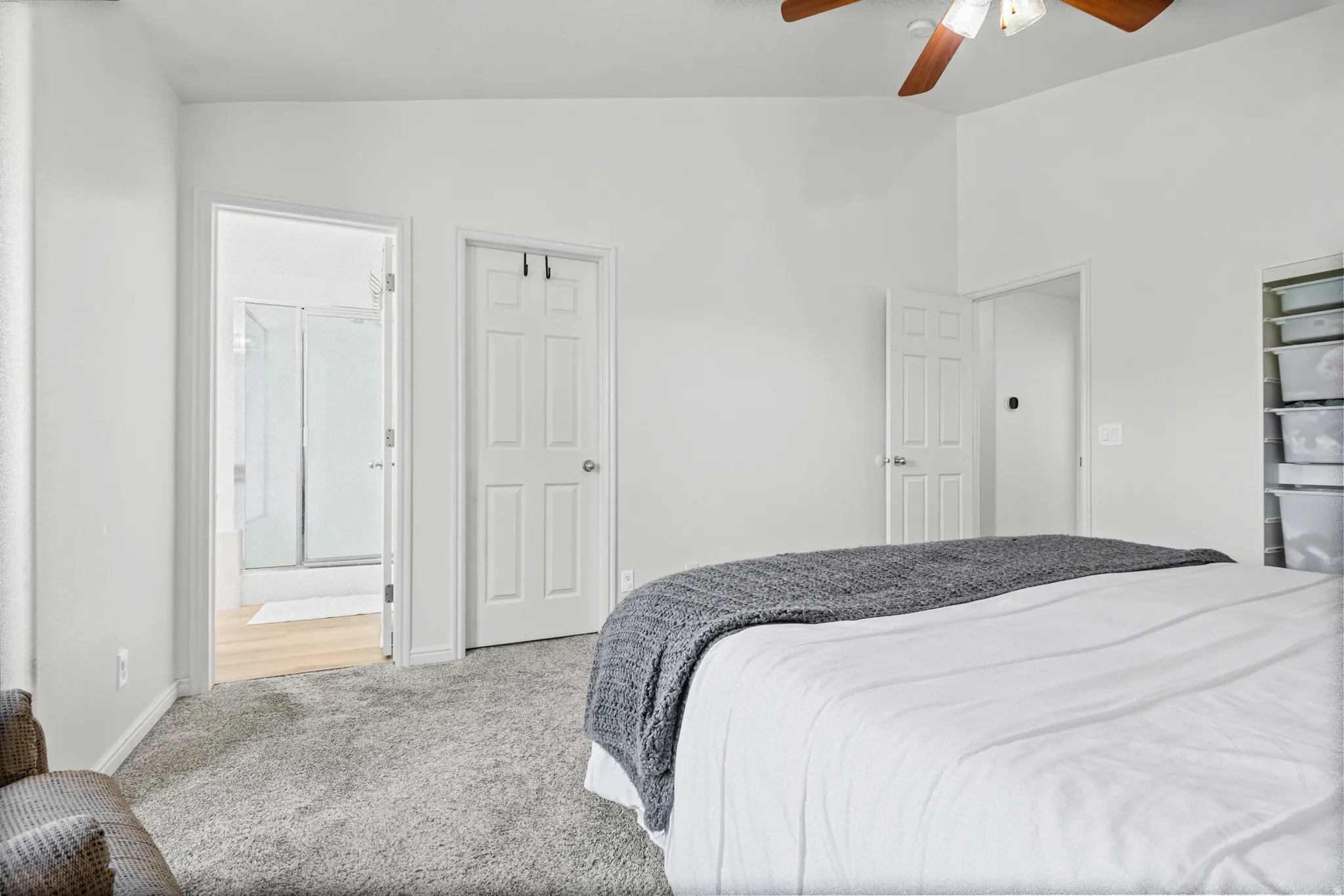 Spacious bedroom featuring vaulted ceilings, neutral-toned carpeting, and a ceiling fan with integrated lighting