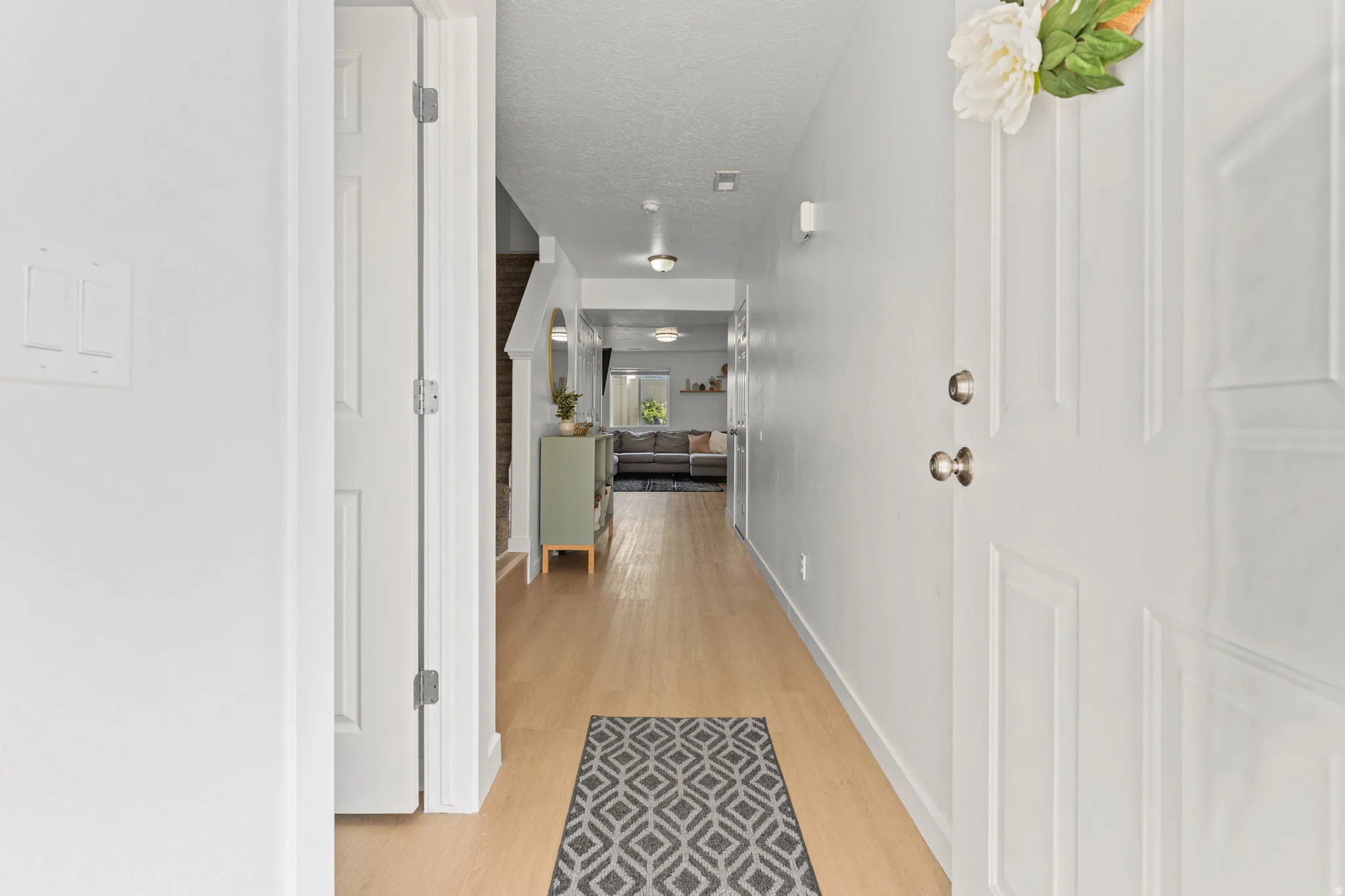 Bright entryway featuring light wood-finish flooring, white walls, and a white paneled door