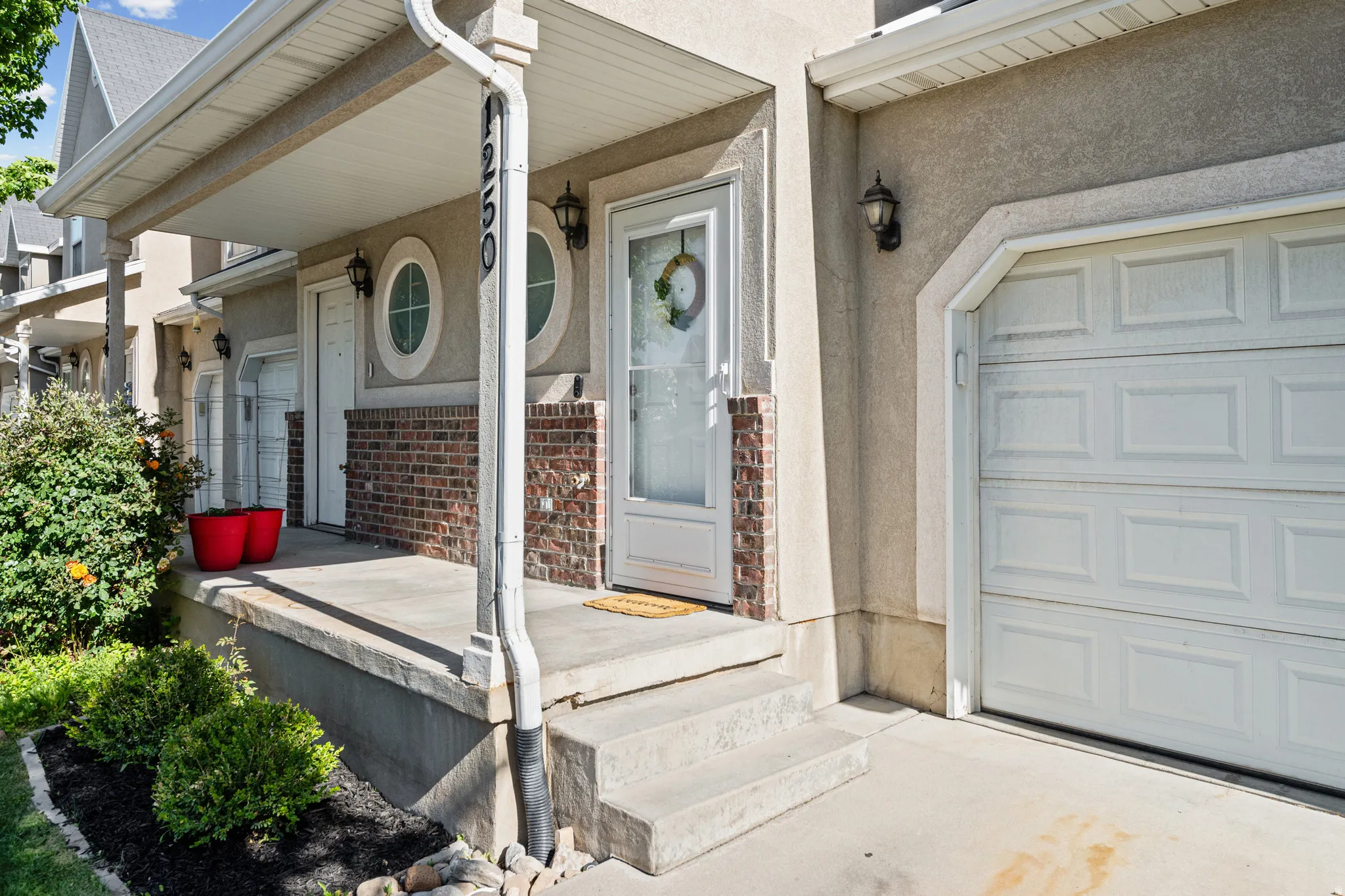 Stucco and brick exterior with a covered porch and white garage door