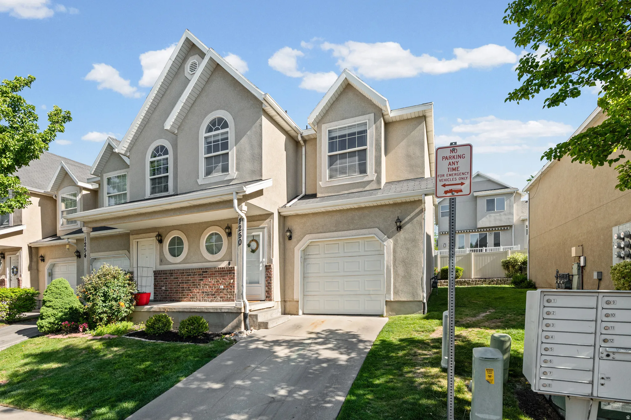 Multi-level residence featuring stucco and brick facade, arched windows, an attached garage, and a covered front entry