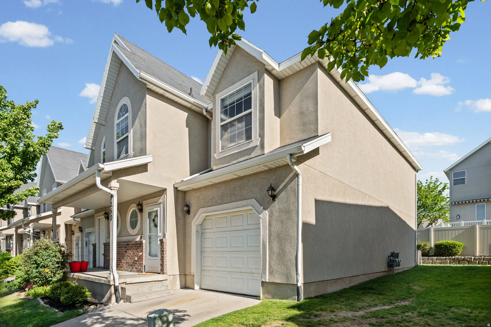 Stucco exterior featuring an attached garage and a covered front porch