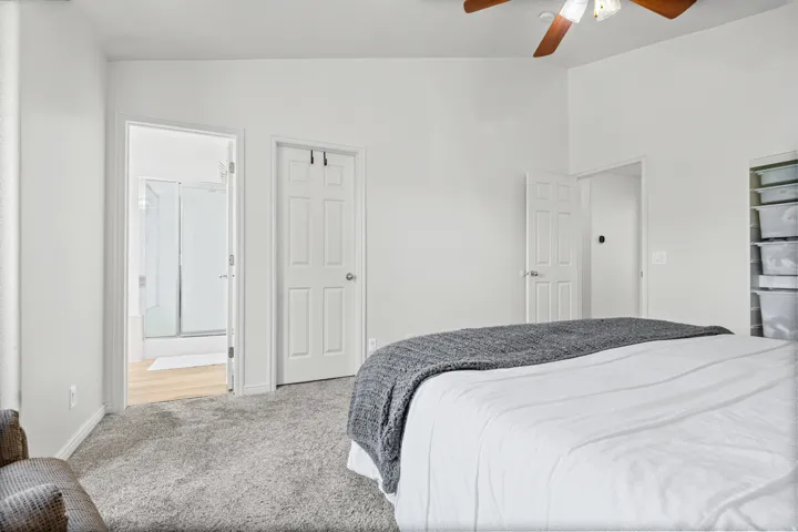 Spacious bedroom featuring vaulted ceilings, neutral-toned carpeting, and a ceiling fan with integrated lighting