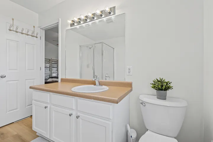 Bathroom featuring a white vanity with cabinet storage, an integral sink, and a light-toned countertop