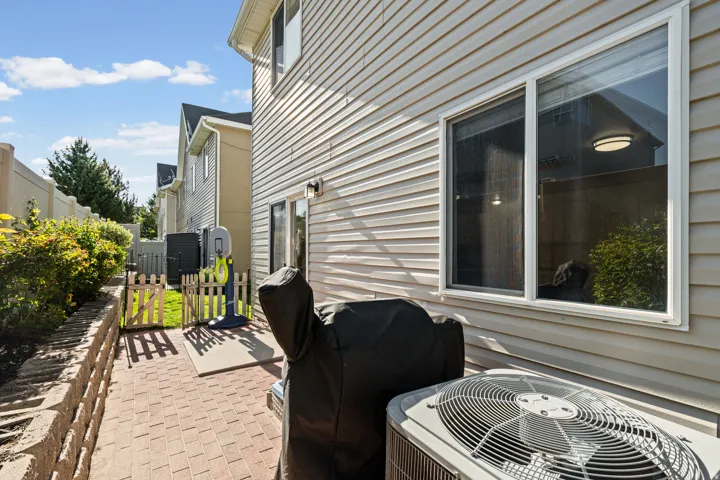 Side patio featuring brick paver flooring and a retaining wall with shrubbery