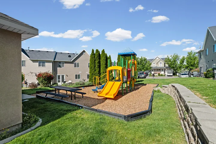 Outdoor play area featuring a multi-level play structure with slides and climbing elements, set on a wood chip surface