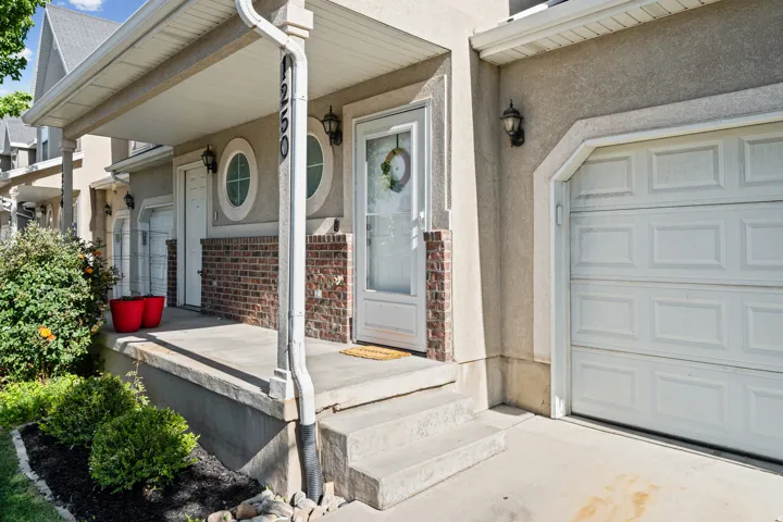 Stucco and brick exterior with a covered porch and white garage door