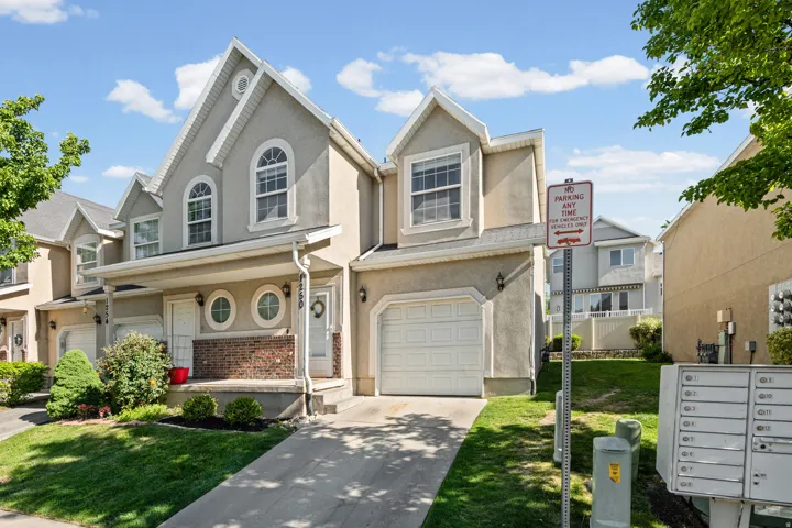 Multi-level residence featuring stucco and brick facade, arched windows, an attached garage, and a covered front entry