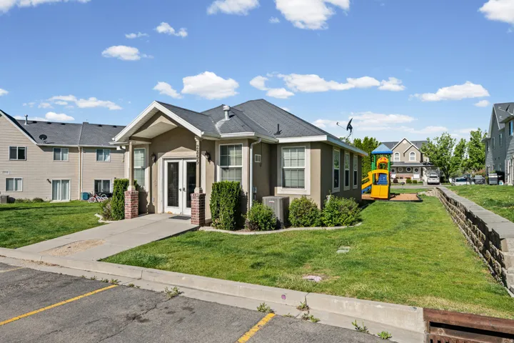 Exterior building featuring a stucco finish, covered entryway, double glass doors, and multiple windows